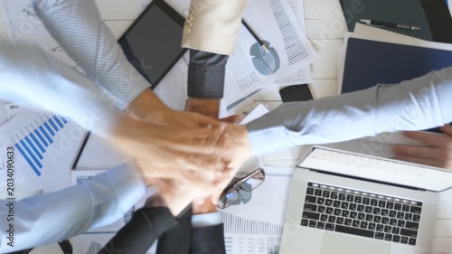 Top view to hands of business people celebrating achievement. Group of employers stacked arms together one by one in unity showing joyful. Creative team working at modern office. Success concept
