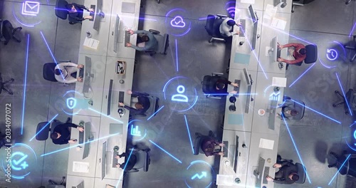 Top Down View of Open Plan Office With Diverse Staff Working at Computer Stations as Linked Visualization Layer Appears, Luminous Blue Beams and Icons Reflect Email, Data Protection and Tracking.