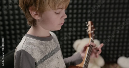 Boy Play Music on Ukulele Instrument in Home Studio. 4K 10-bit