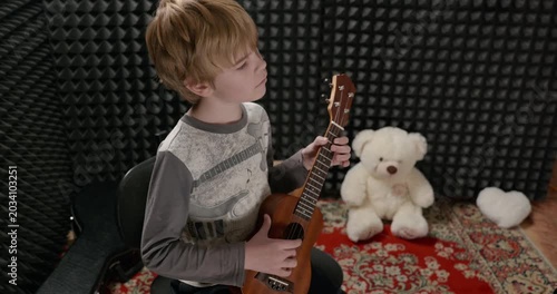 Boy Play Music on Ukulele Instrument in Home Studio. 4K 10-bit