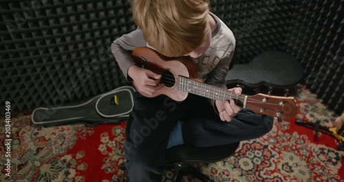 Boy Play Music on Ukulele Instrument in Home Studio. 4K 10-bit