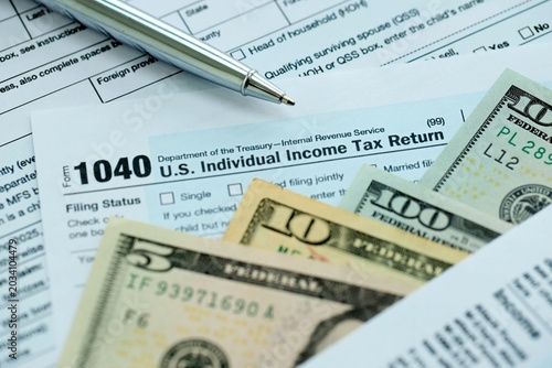 Foto 1040 Individual Income tax return form and pen with dollars money bills on accou