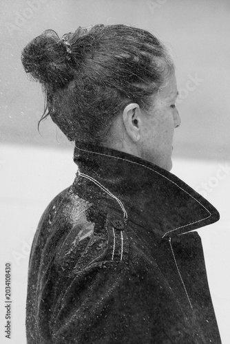Brunette Frau steht mit ihrem Regenmantel voll im Regen