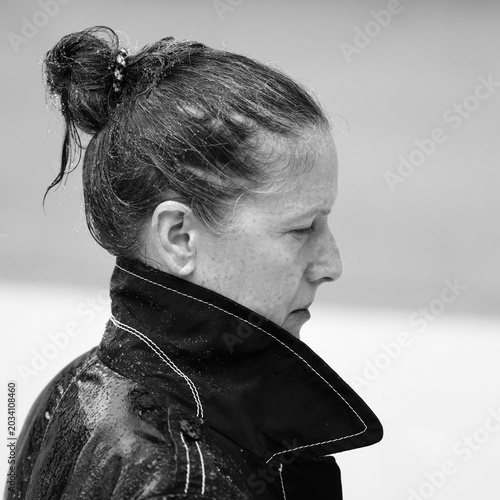 Brunette Frau steht mit ihrem Regenmantel voll im Regen