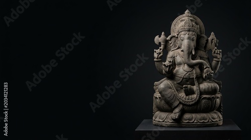 Detailed stone sculpture of the hindu deity ganesha sitting in a traditional pose captured in a professional studio light photograph