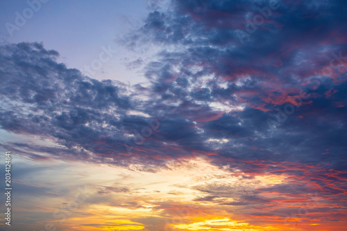 Bilde på lerret A breathtaking, vibrant sunset sky filled with dramatic, textured clouds painted in brilliant shades of fiery orange, deep magenta, and soothing twilight purple, capturing the serene beauty