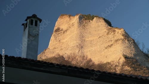 View of the Melnik sand pyramids, with a house chimney in the foreground.
