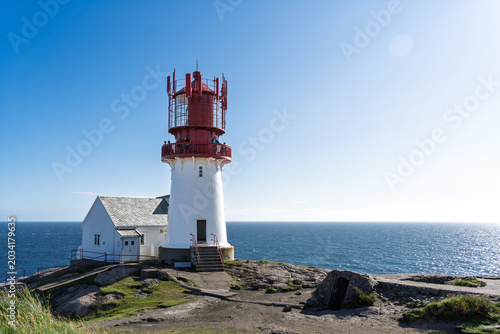 Remote North Sea navigation with Lindesnes Lighthouse standing above exposed rocky coastline in southern Norway for maritime travel and coastal tourism. Copy space