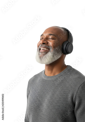 mature african american man with silver beard and warm brown skin in charcoal sweater, wearing black wireless headphones, eyes closed, smiling on white high-key studio background with copy space.