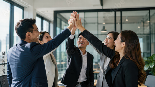 Business team high five office collaboration happy coworker group meeting success teamwork celebration professional workplace modern interior asian adult suit