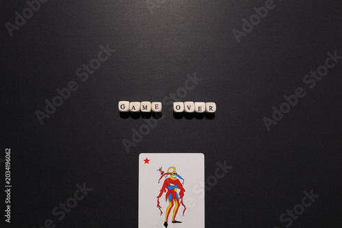 Bild auf Leinwand Game over spelled with letter tiles above a joker card on dark background, symbolizing failure, defeat, collapse and high stakes risk