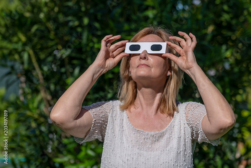 A woman has special glasses to observe the sun during an eclipse