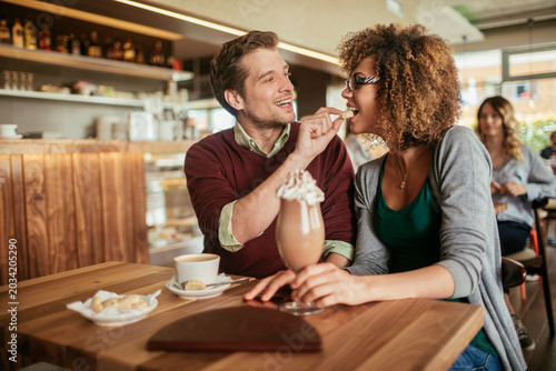 Smiling couple sharing dessert in cozy cafe