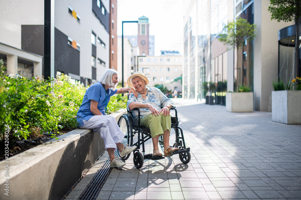 Ταπετσαρία Senior patient in wheelchair talking with her caregiver.