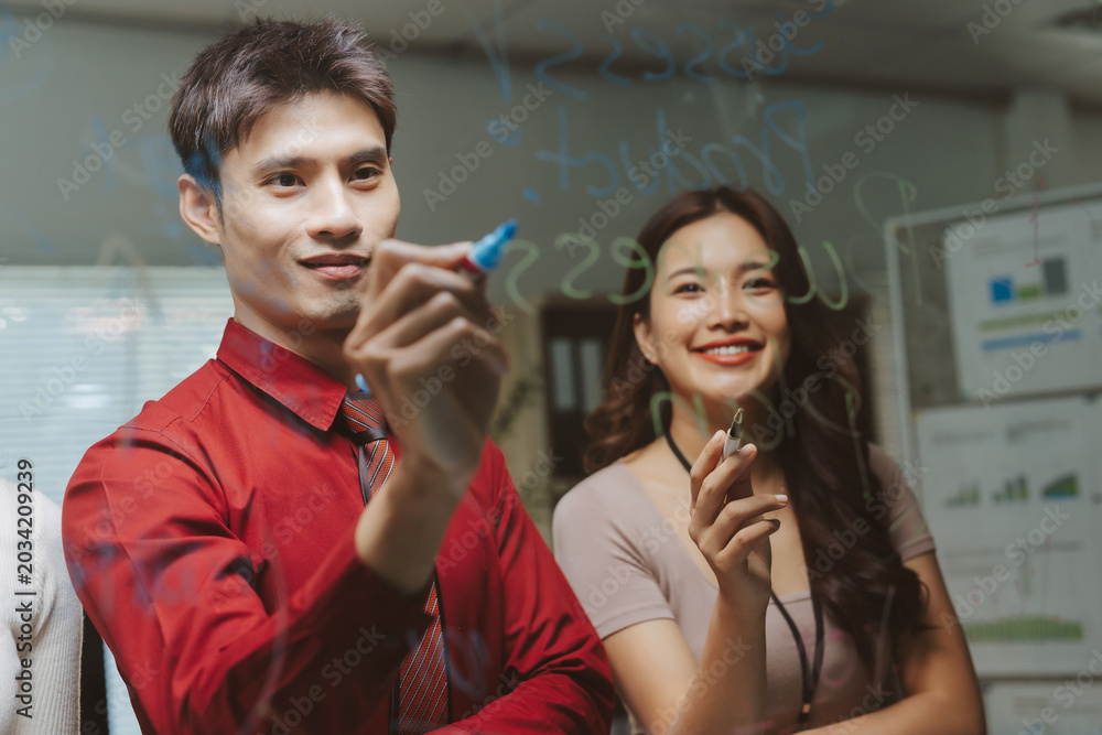 Φωτογραφία Collaborating business people writing on a transparent board, developing new str
