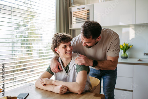 Fotografía Father supporting teenage son at home during everyday moment.