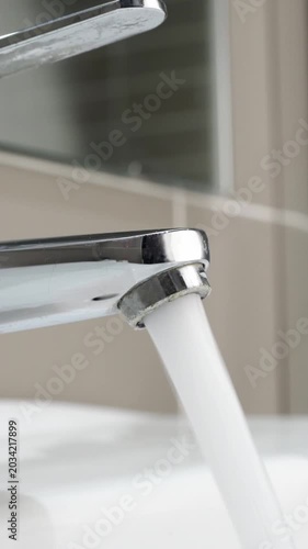 Hand close up water from faucet in sink, faucet,man stop wasting water, flood, running water for washing in hotel bathroom