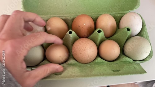 Hand sorting through fresh farmed organic eggs in the package