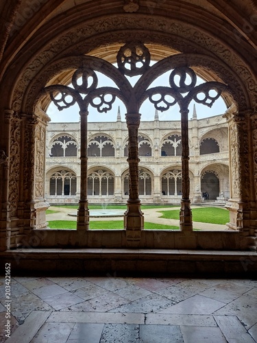 Tableau sur toile Beautiful gothic carved stone arch window overlooking a historic monastery court