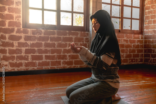 Obraz na plátně Muslim woman wearing hijab sitting and peacefully pray in the room