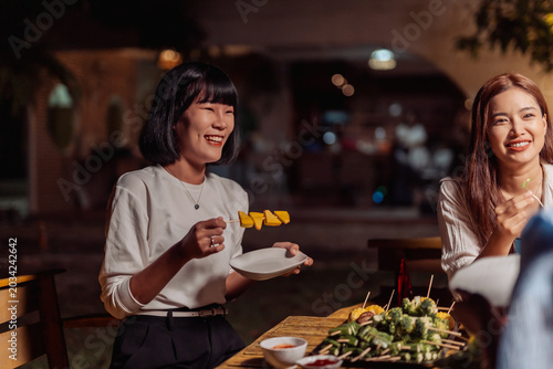 Fotografía Asian friends gathering for an enjoyable outdoor barbecue party at night, sharin