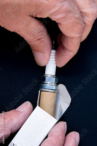 Mechanic removes a new sparkplug from its box