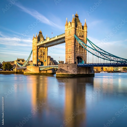 Iconic bridge crossing wide river at sunrise