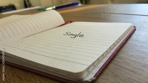 Open notebook with handwritten word 'Single' on a wooden table