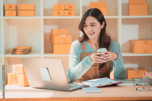 Successful SME startup business woman checking online store sales and preparing parcel boxes for shipping.