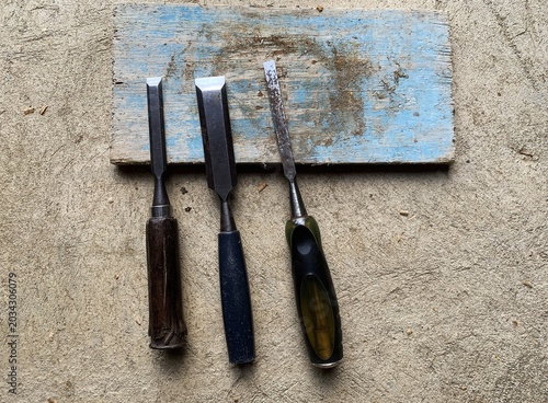 Fotografía Three chisels rest on a worn wooden block. carpentry instrument.