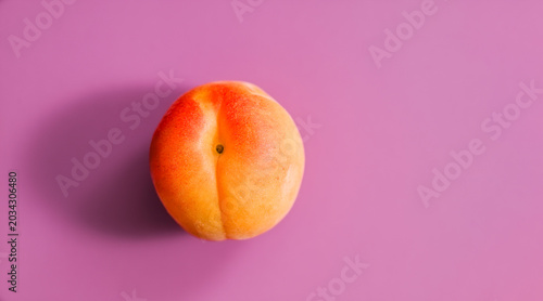 Ripe apricot with vivid orange and yellow tones centered on a saturated purple background, creating a fresh, colorful minimal still life perfect for food and lifestyle use