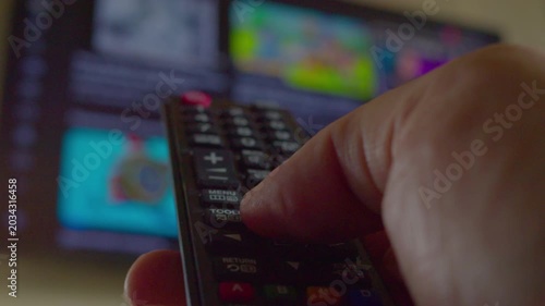 First-person view of a hand using a remote control to change channels and then turn off a modern TV, close-up, shallow depth of field