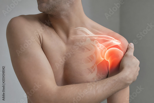 Man clutching his chest with a glowing red lung and ribcage visible through his skin in a gray room interior closeup