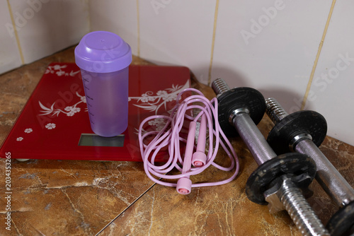 Quadro em tela Fitness equipment including a red digital scale, pink jump rope, and dumbbells on a marble floor