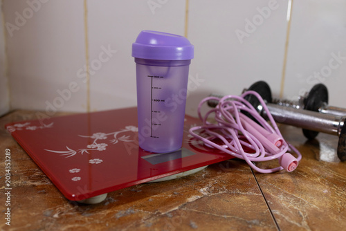 Tableau sur toile Fitness equipment including a red digital scale, pink jump rope, and dumbbells on a marble floor
