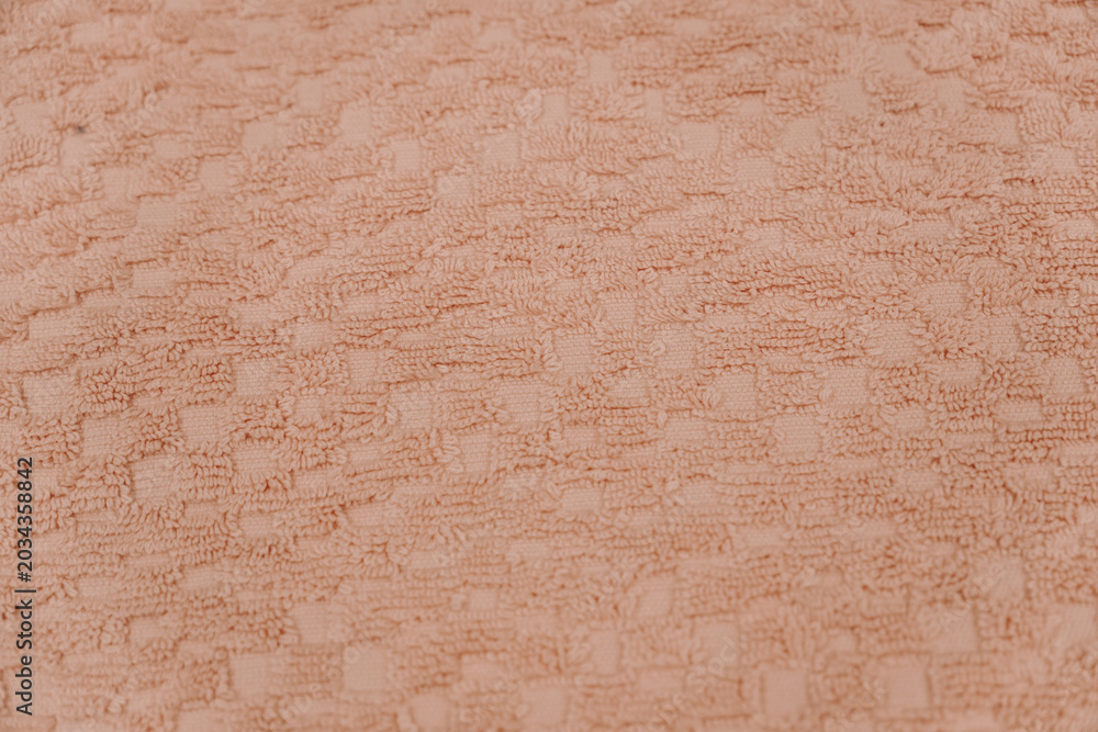 Fototapeta premium Close up texture of soft pink towel material with geometric woven pattern. Bathroom comfort and textile design concept.