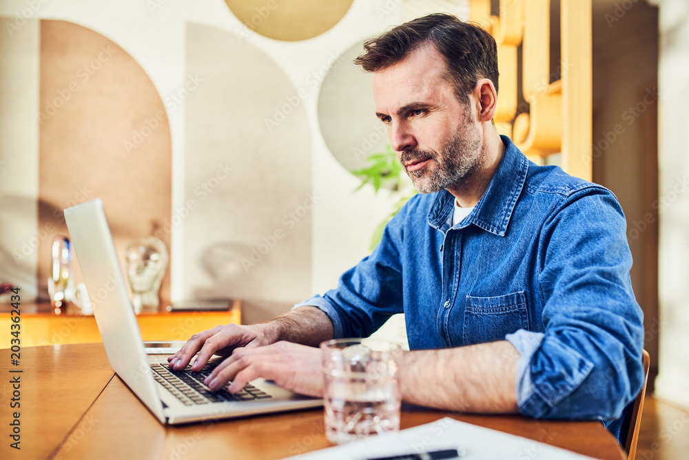 Fototapeta premium Man working on laptop at dining table at home