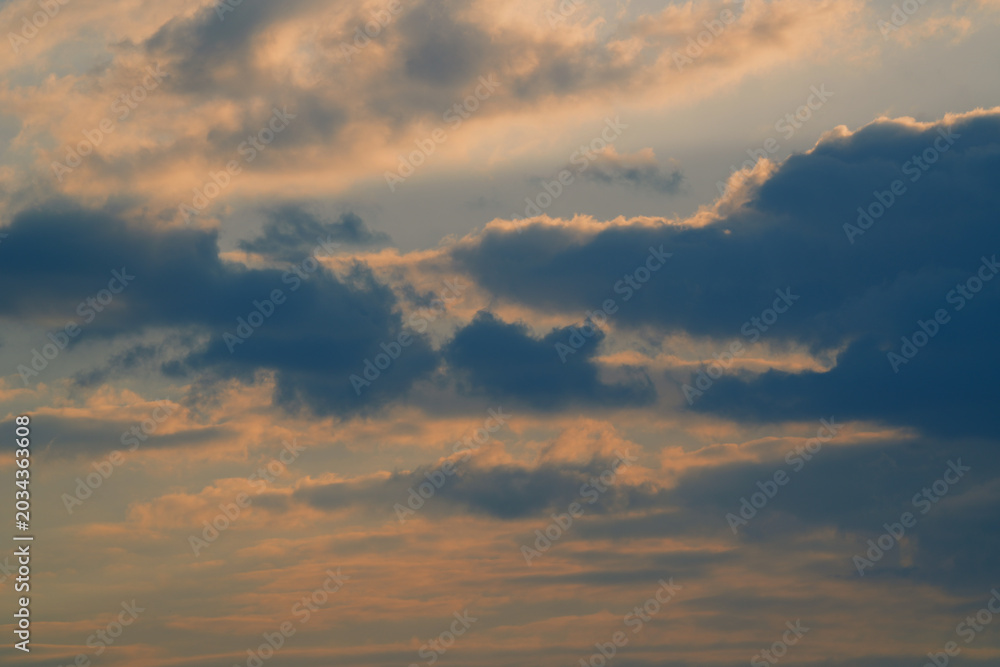 Obraz premium Epic sunset sky with fluffy clouds in golden and blue tones. Cinematic golden hour sunlight. Dreamy magic atmosphere of abstract evening heaven. Beautiful nature background for inspiration.
