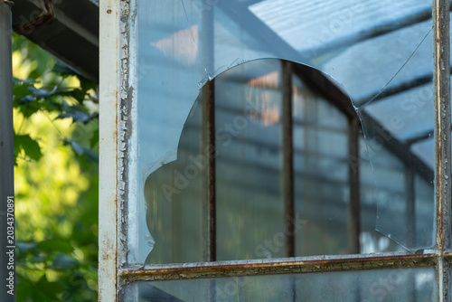 Fotografie Broken glass pane in old greenhouse