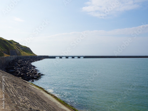Paisaje de la costa normanda en Francia, con un puente en el horizonte sobre el mar azul y el cielo con nubes, viajando en verano de 2022