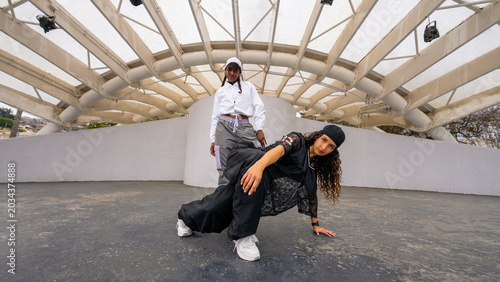 Fotografie Young women performing a dynamic hip hop street dance under a modern canopy