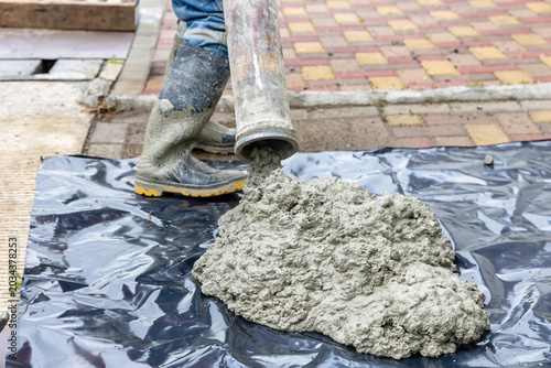 Fotografía Leftover wet concrete discharged from concrete pump pipeline onto plastic sheet