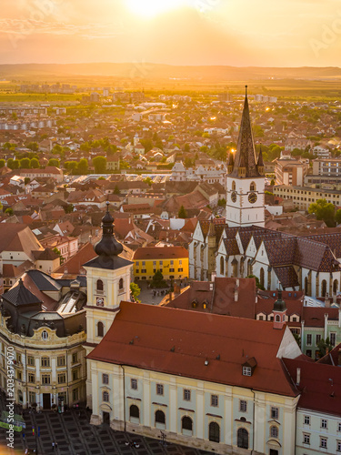 Aerial sunset view of the Great Square in Sibiu Romania, showing historic buildings, the Catholic and Lutheran Church, and the council tower, sunset landscape. Sibiu Transylvania landmarks.