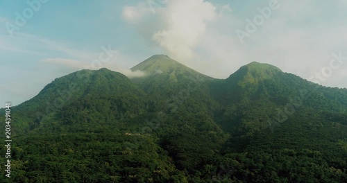 Aerial drone view of tropical forest with soft sunlight illuminating mountain landscape