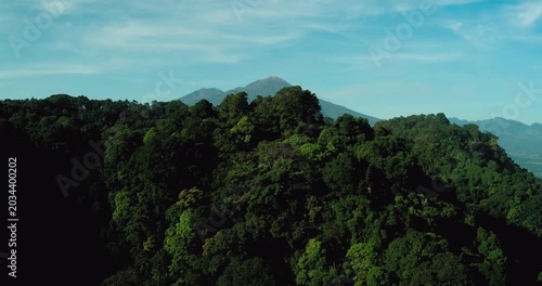 Drone shot of tropical forest with heavenly sun rays through clouds
