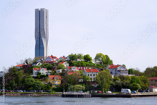 Colony of small wooden historic houses on the Slottsberget mountain with the tallest Scandinavian building Karlatornet skycraper in Lindholmen in background, Gothenburg, Sweden