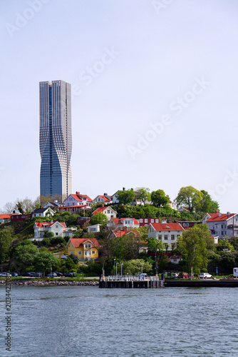 Colony of small wooden historic houses on the Slottsberget mountain with the tallest Scandinavian building Karlatornet skycraper in Lindholmen in background, Gothenburg, Sweden