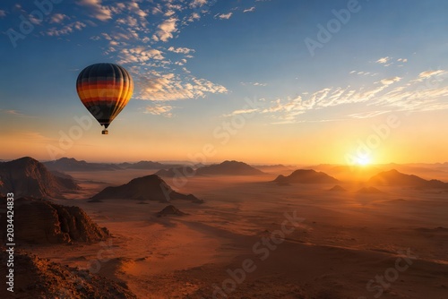 Colorful striped hot air balloon floating above vast desert landscape at sunrise with rocky formations and golden light, symbolizing adventure, travel, and freedom