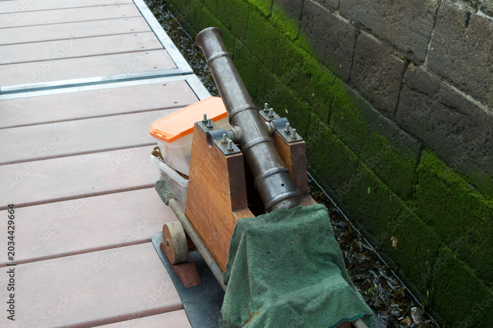 Fototapeta premium Vintage cannon on the dock. Four inch blank firing cannon used in reenactments, waiting to be loaded onto a ship.