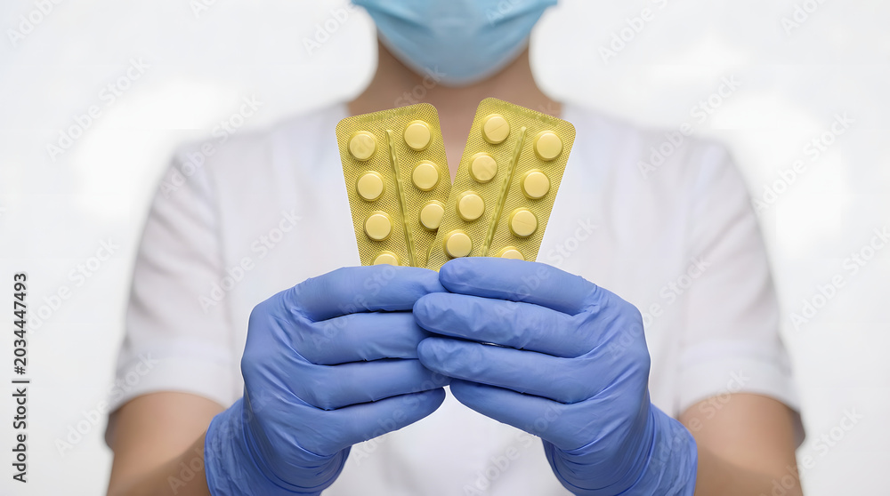 Obraz premium Yellow prescription medicine capsules isolated on white background held forward by a nurse in blue medical gloves